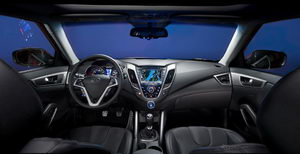 
Vue de la planche de bord et du poste de conduite de la Hyundai Veloster. L'ensemble est futuriste et sportif, avec un rtro-clairage bleut assez valorisant.
 